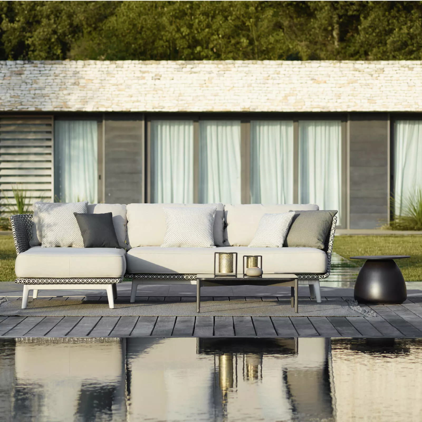 Dedon Mbarq Lounge in einem modernen Garten mit Pool im Vordergrund und einem stilvollen Haus im Hintergrund 