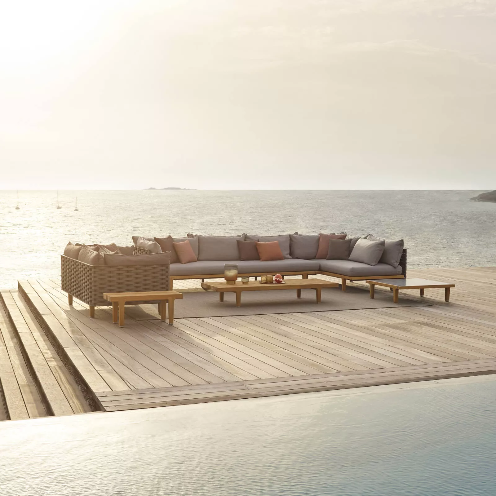 Dedon Sealine Kollektion Lounge-Sofa auf einer Terrasse mit Blick auf das Meer und Segelboote im Hintergrund 