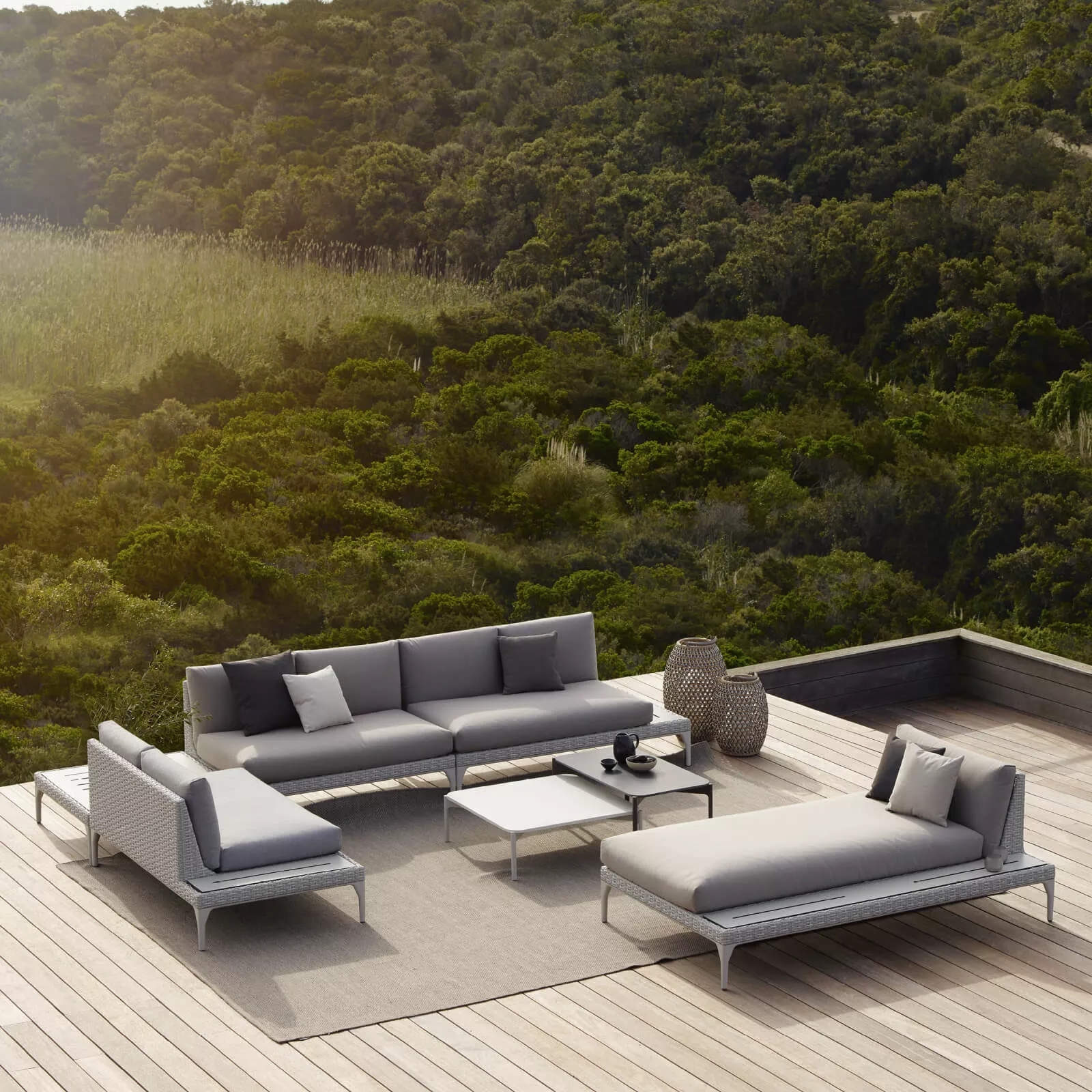 Dedon Izon Kollektion graue Outdoor-Möbel auf einer Terrasse mit Blick auf eine grüne Landschaft 